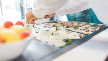 Uno chef prepara del cibo al bancone, con diversi ingredienti e utensili.