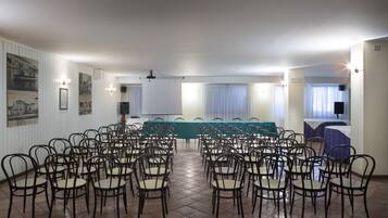 A conference room with rows of chairs, a long table, and a projector screen.