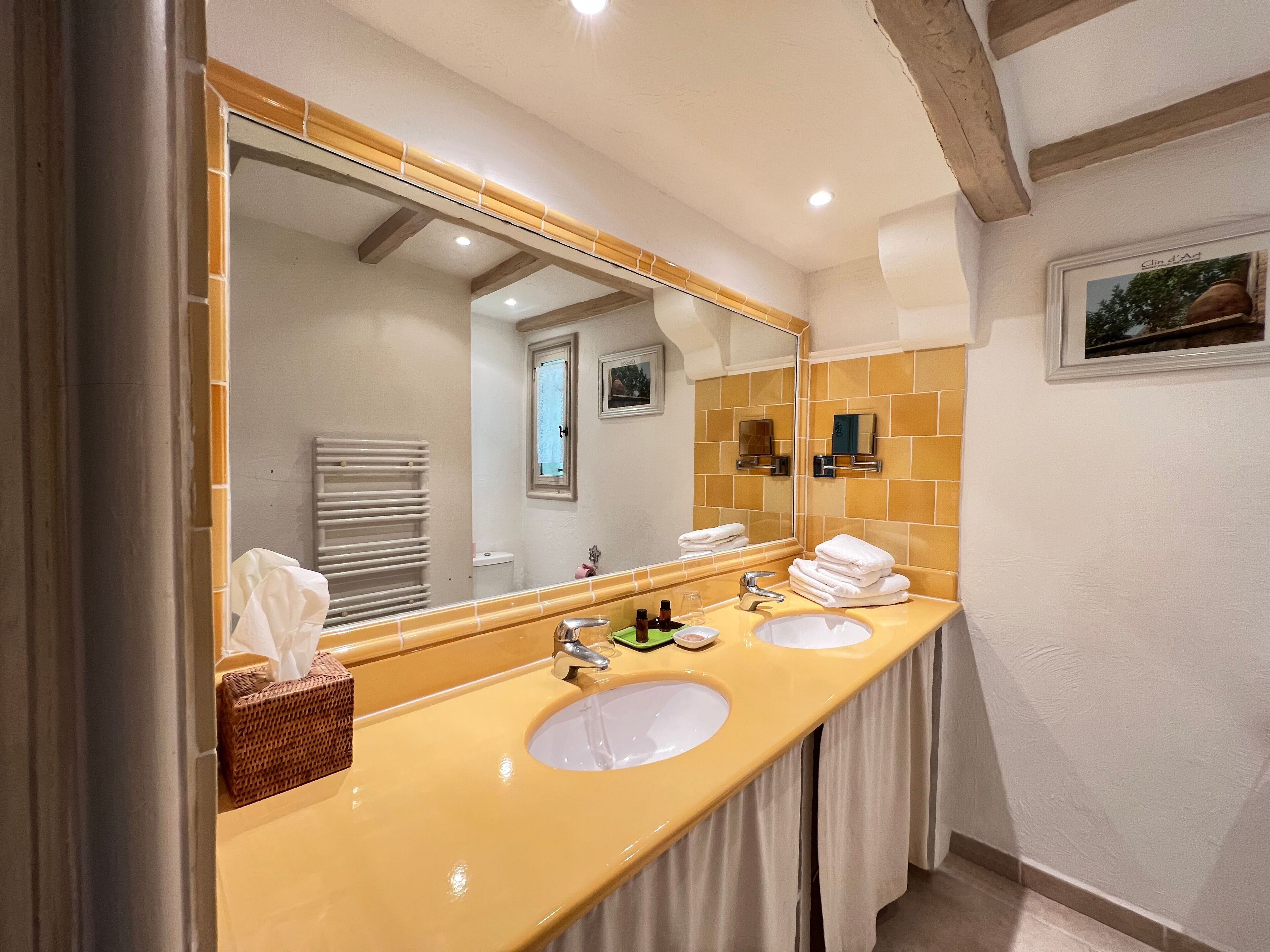 A bathroom with two sinks, a large mirror, and a towel rack.