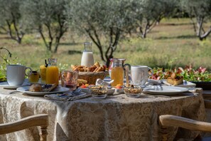 A breakfast table set outdoors with various food items and drinks.