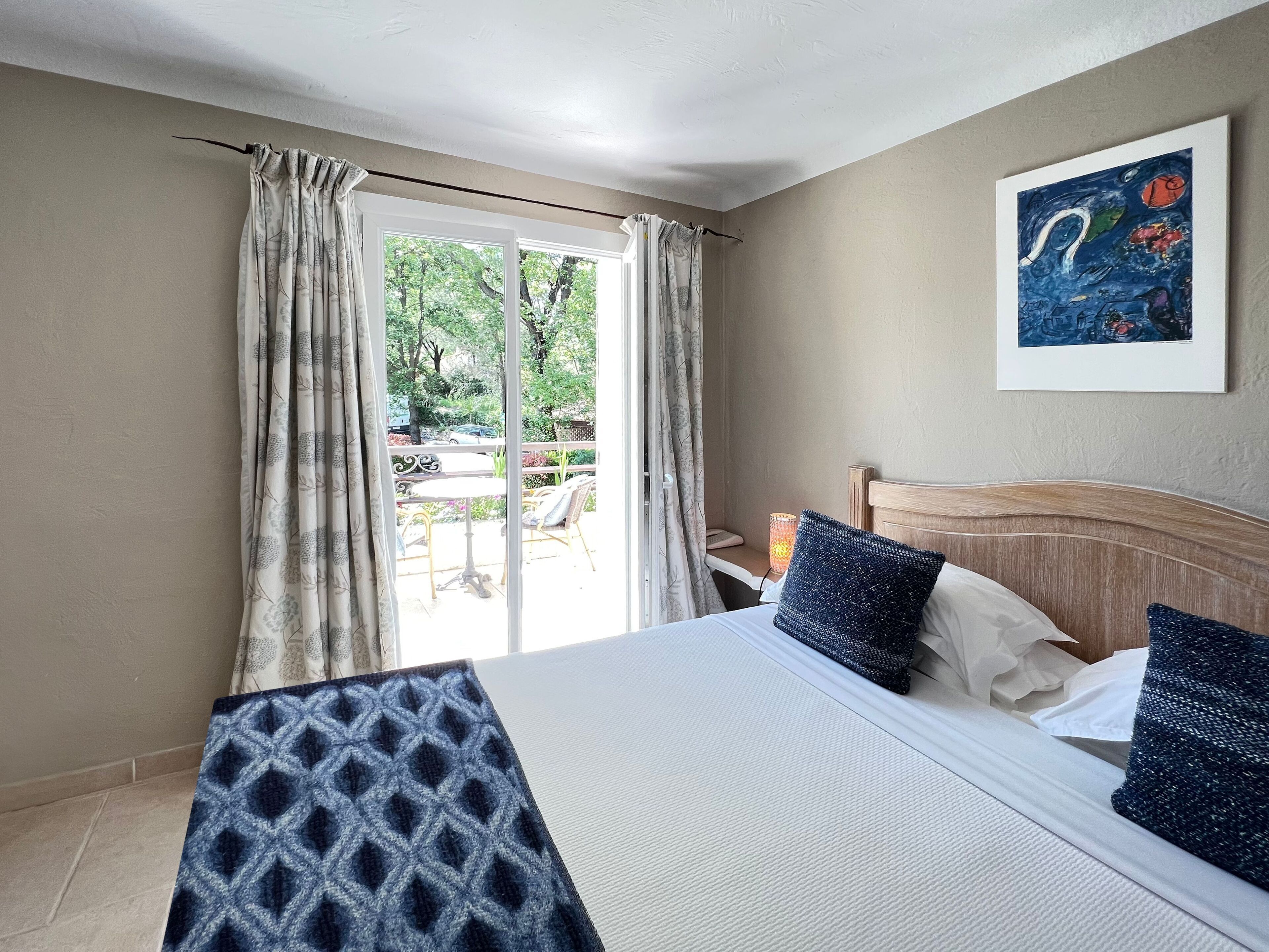A bedroom with a bed, a nightstand, a lamp, and a painting on the wall.