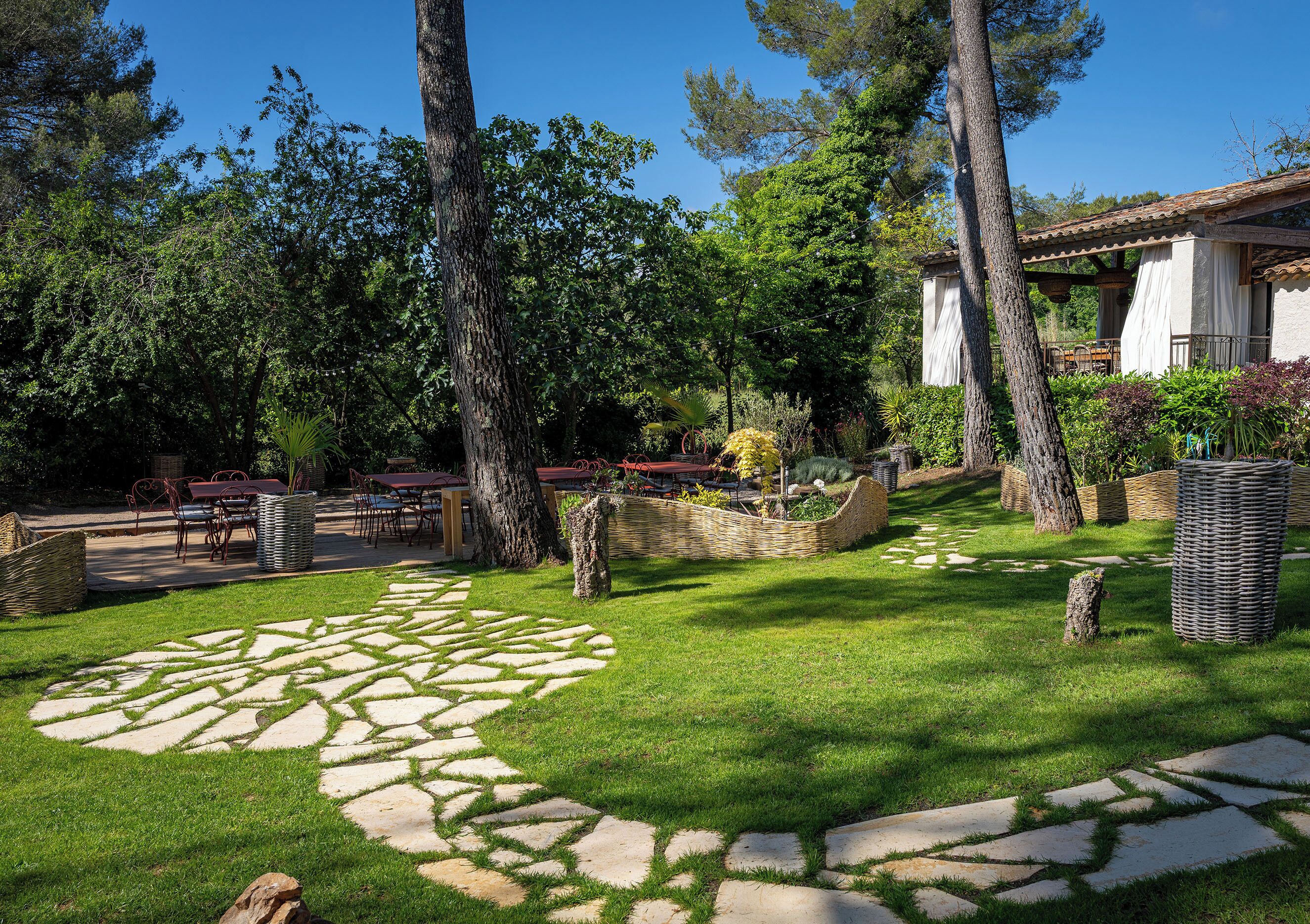 Un giardino con vialetti in pietra, alberi e mobili da esterno.