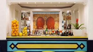 Una zona de bar con pared de piedra, estantes con botellas y una pila de naranjas.