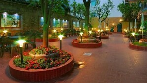 Un espacio al aire libre con parterres circulares, árboles y mobiliario exterior.