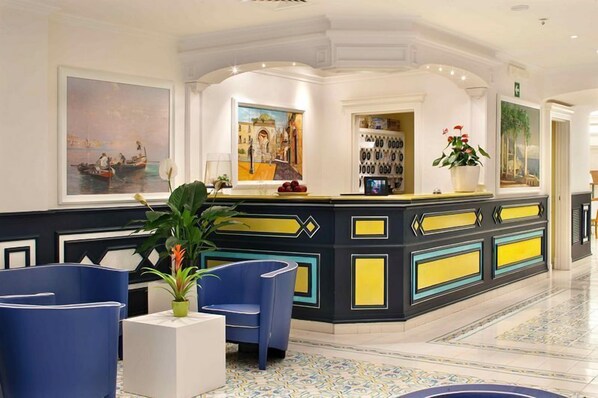 A reception area with a counter, chairs, and artwork on the walls. - Hotel Astoria Sorrento (Sorrento)