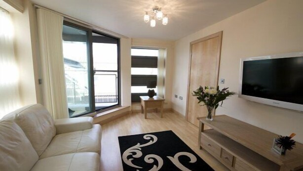 A modern living room with a sofa, a TV, a wooden cabinet, and a large window. - Dreamhouse Manchester Deansgate (Manchester)