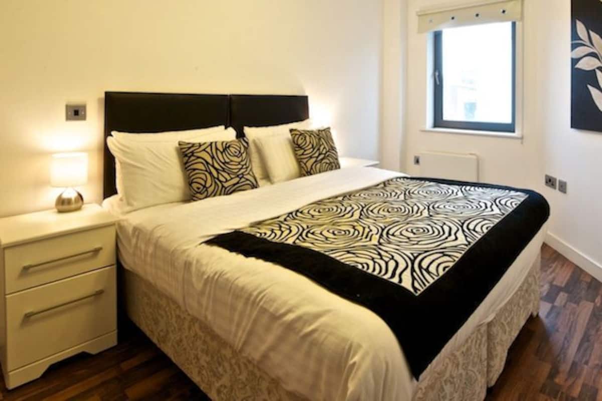 A neatly arranged bedroom with a bed, bedside table, and a window with a view.