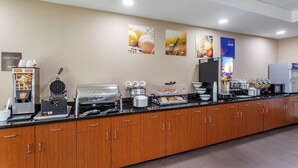 A buffet setup with various food stations, including a waffle maker, a coffee station, and a fruit display. - Comfort Inn & Suites Atoka-Millington (Atoka)
