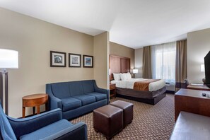A hotel room with a bed, a sofa, a desk, and a small table. There are three framed pictures on the wall. - Comfort Inn & Suites Atoka-Millington (Atoka)