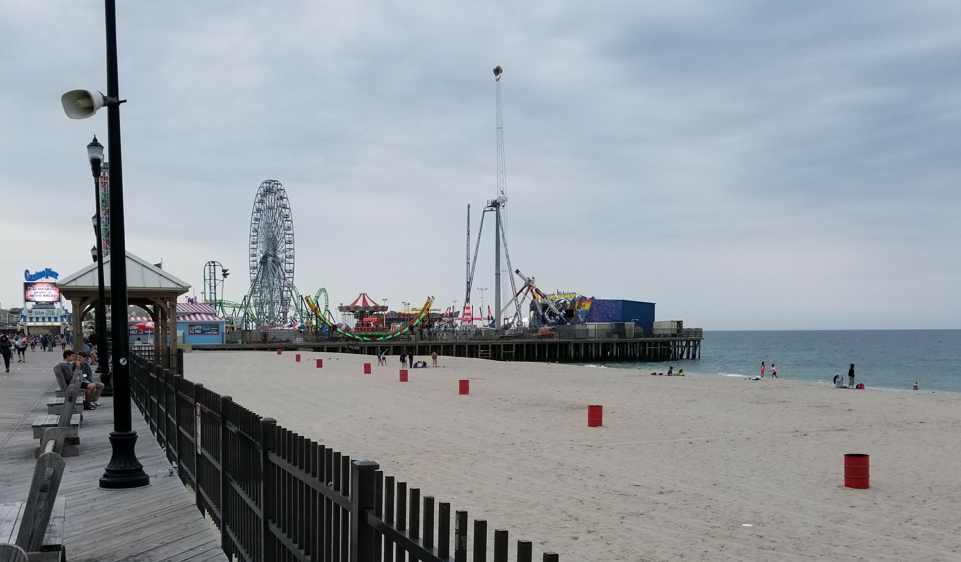 Una playa con un paseo marítimo, una noria y atracciones.