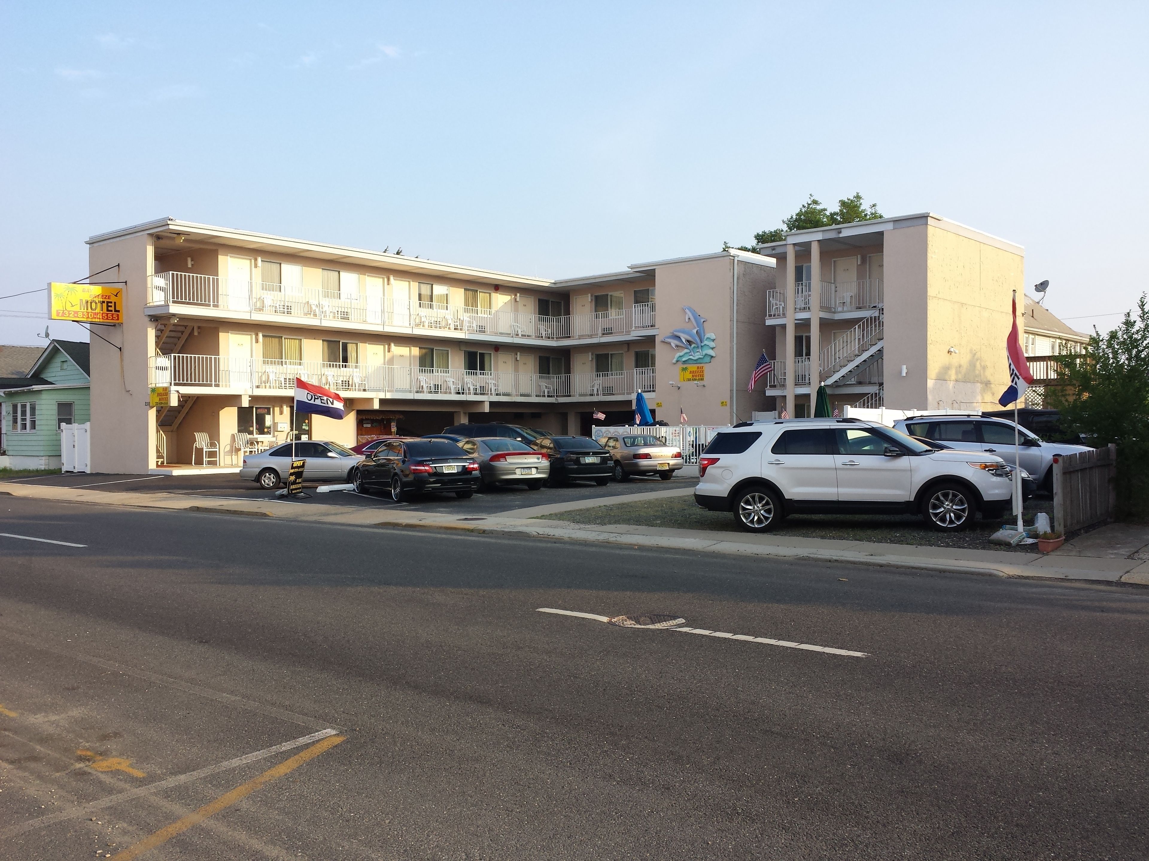 A motel with multiple floors, outdoor seating, and several cars parked in front.