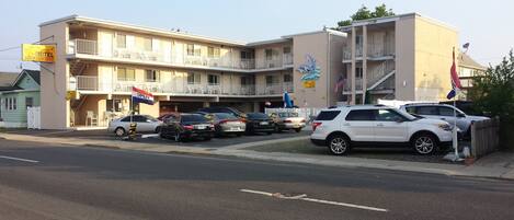 A motel with multiple floors, outdoor seating, and several cars parked in front.