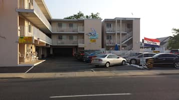 Un motel con estacionamiento, varios coches aparcados y un letrero que indica que está abierto.