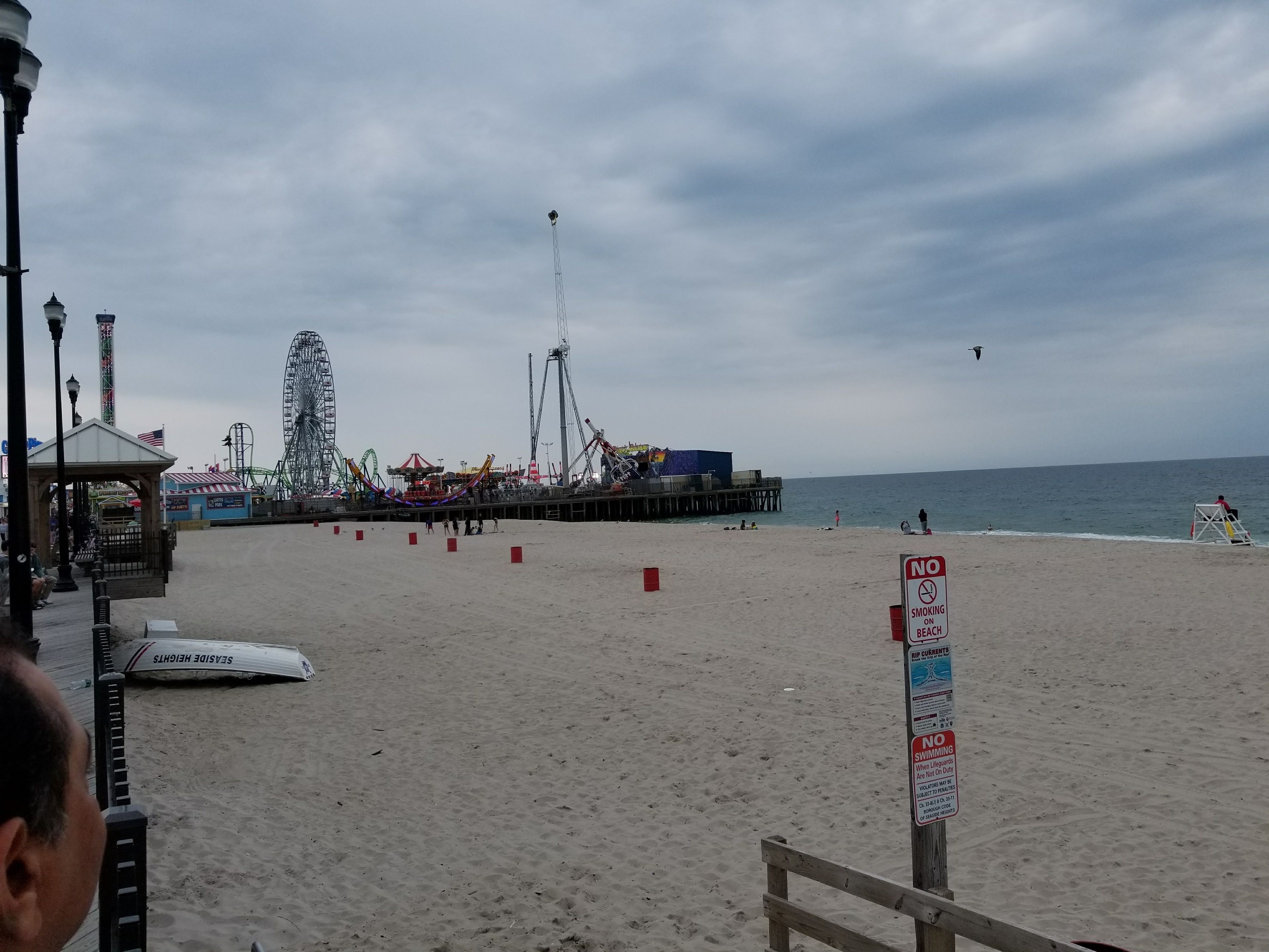 Una playa con un muelle, una noria y un puesto de salvavidas.