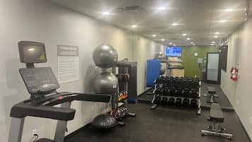 A gym with cardio equipment, dumbbells, and a treadmill.