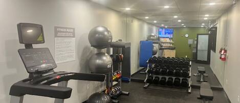 A gym with cardio equipment, dumbbells, and a treadmill.