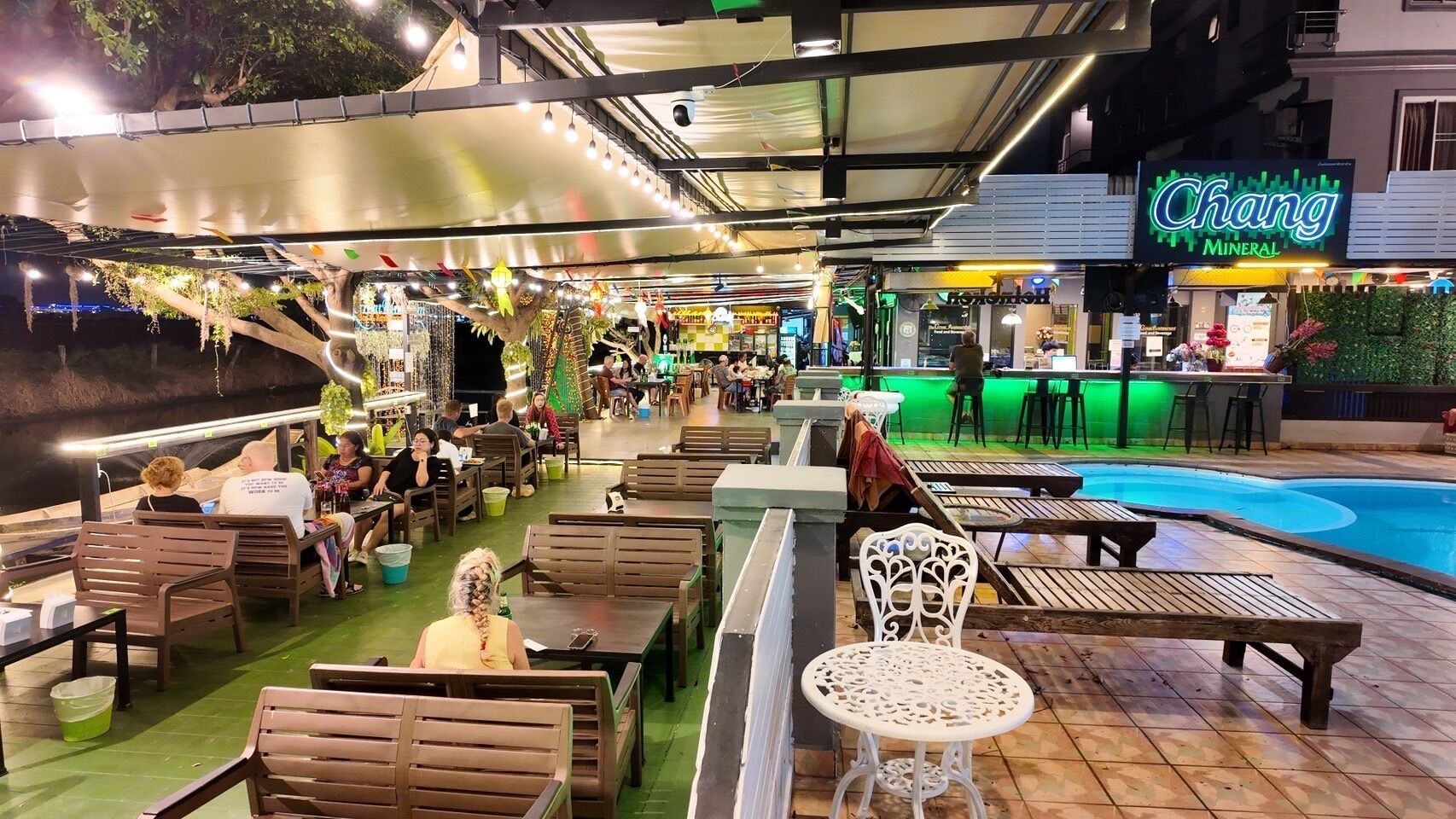 Un área de bar al aire libre con asientos y una piscina.