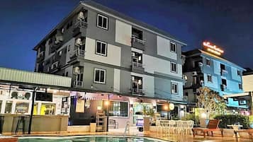 Um hotel com vários andares, piscina, área de estar externa e restaurante à vista.