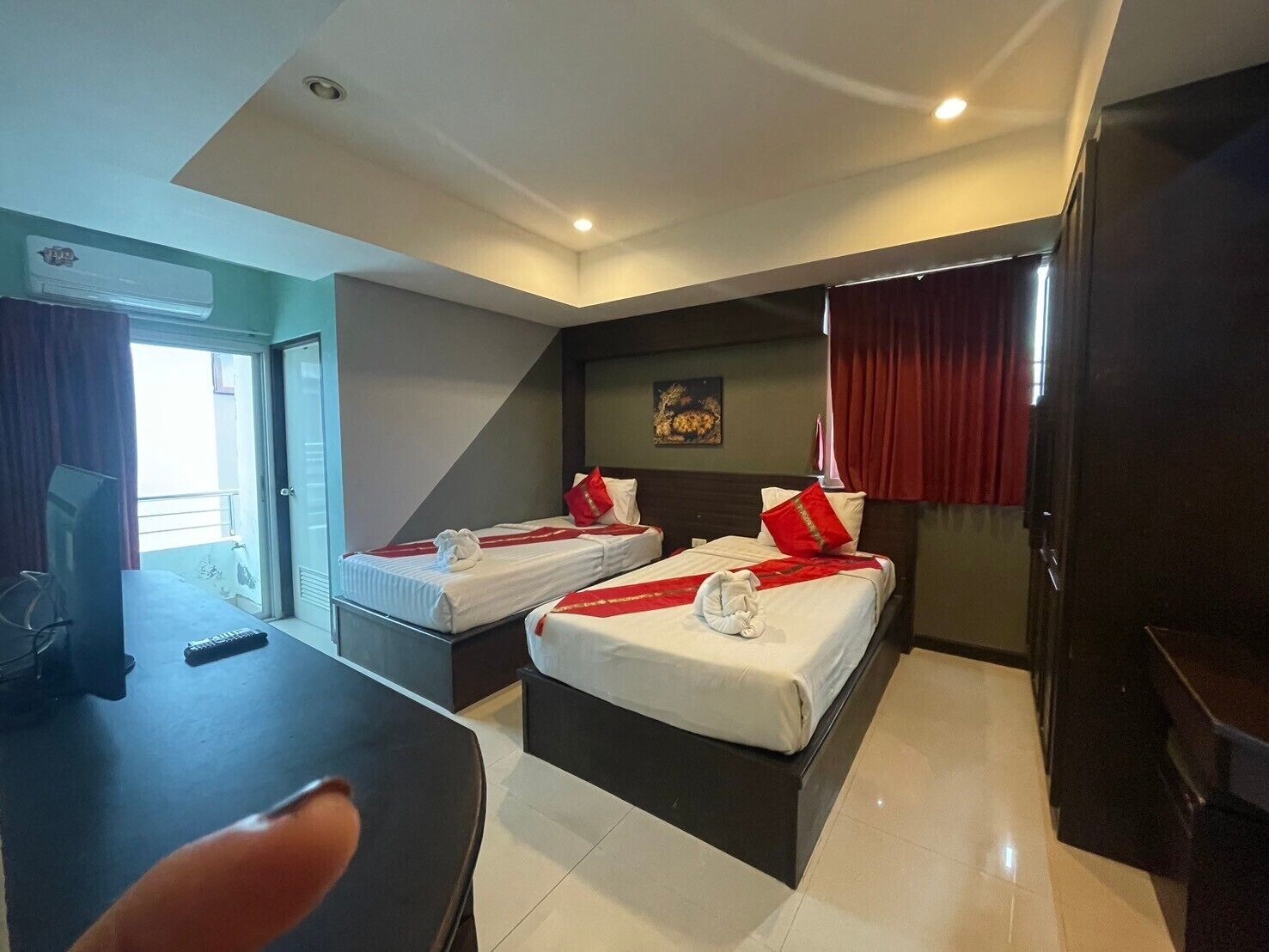 Habitación de hotel con dos camas, un escritorio y una televisión.