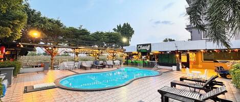 A swimming pool area with lounge chairs and a bar.