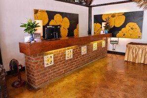 Una recepción con fachada de ladrillo, una máquina de café negra y cuadros con motivos florales en la pared.