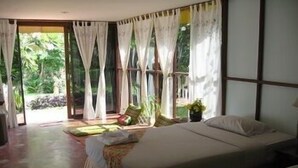Een slaapkamer met een bed, een bank en uitzicht op een tuin.