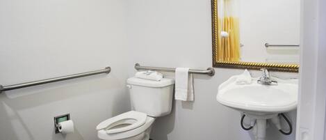 A bathroom with a toilet, a sink, a mirror, and a towel rack.