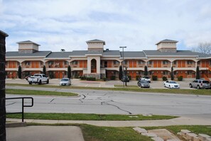 A multi-story hotel with a central courtyard, featuring a parking lot with several cars.