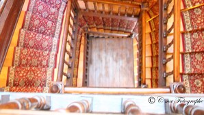 A wooden staircase with ornate railings and patterned carpet. - Majestic (Lourdes)