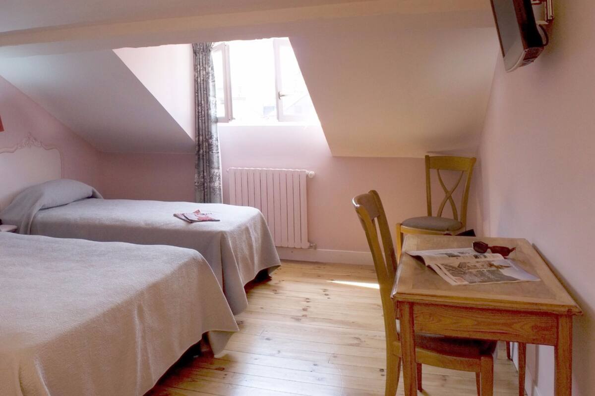 A bedroom with two beds, a desk, and a chair.