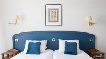 Ein Doppelbett mit weißer und blauer Bettwäsche, zwei Nachttische und ein gerahmtes Bild an der Wand.
