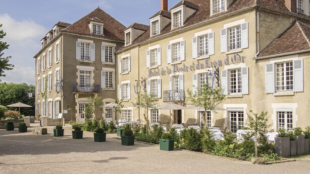 A historic building with a sign reading "Hotel de la Poste et du Grand Or." It features a courtyard with potted plants and outdoor seating. - Hôtel Restaurant de la Poste et du Lion d'Or (Vezelay)