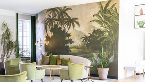 A room with a large mural of a tropical landscape, a white sofa with green cushions, and several green armchairs. - Hôtel Restaurant de la Poste et du Lion d'Or (Vezelay)