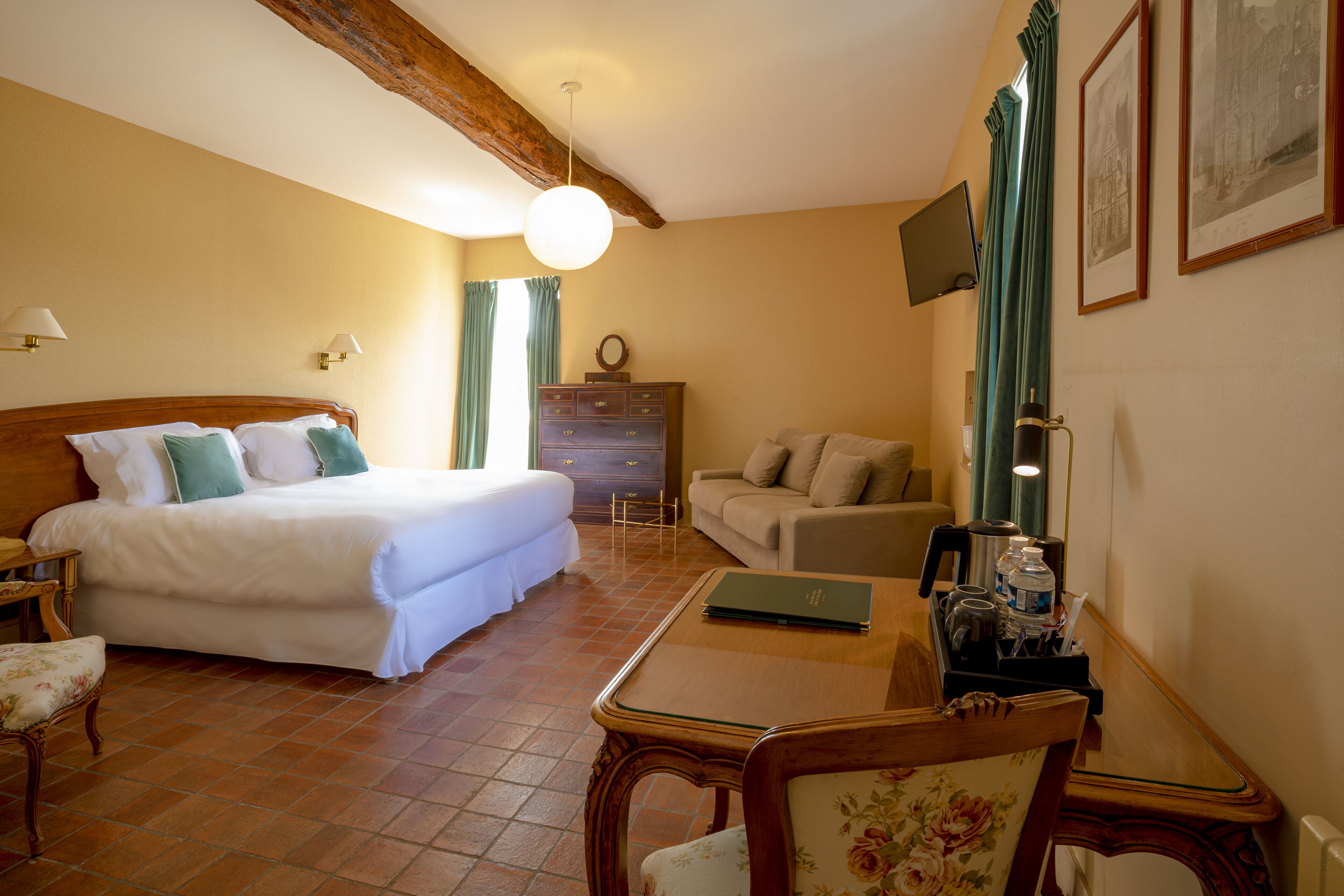 Une chambre d’hôtel avec un lit, un canapé, une table avec un ordinateur portable et une commode.