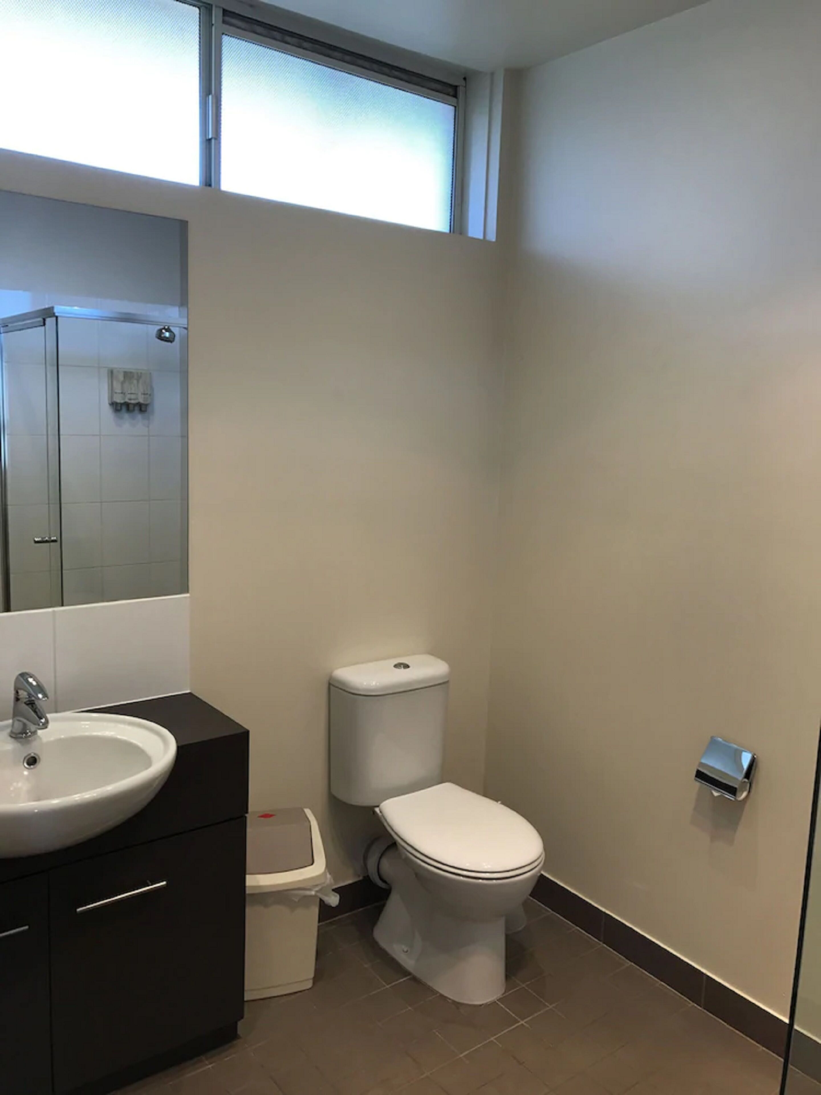 Un baño moderno con lavamanos, inodoro y ducha blancos.