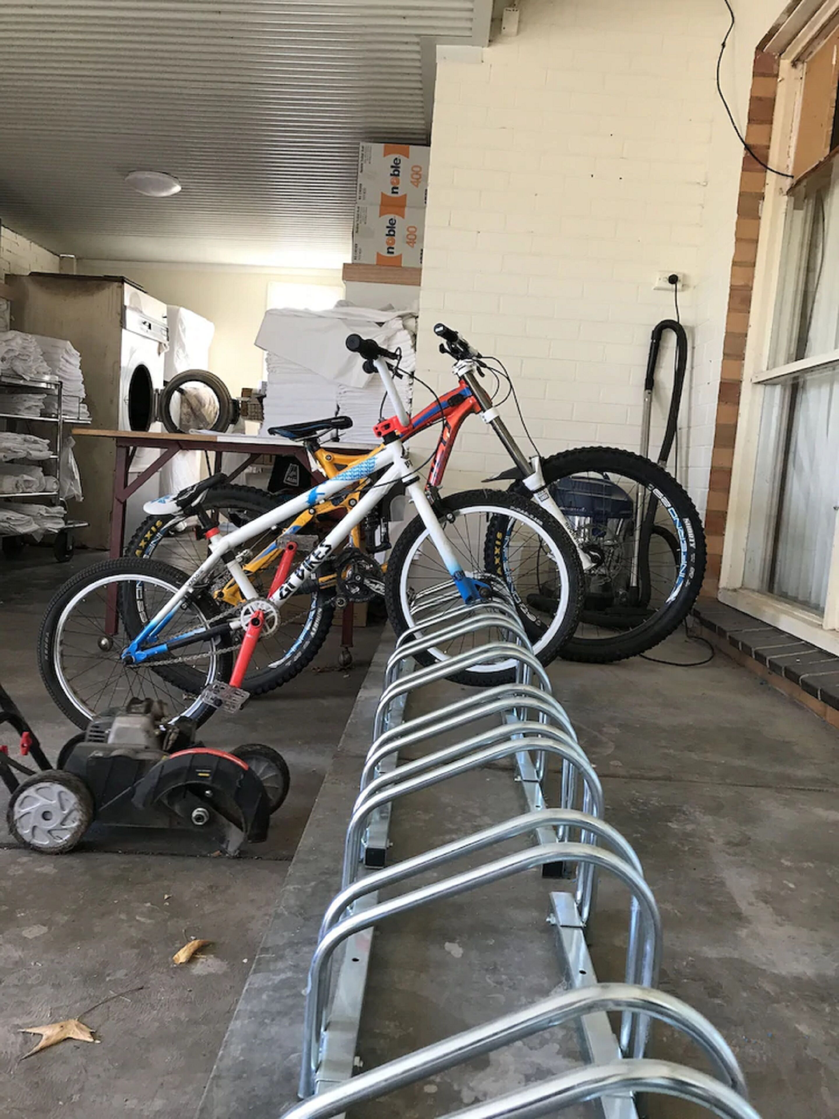 Un aparca bicicletas en un garaje con una lavadora y ropa apilada al fondo.