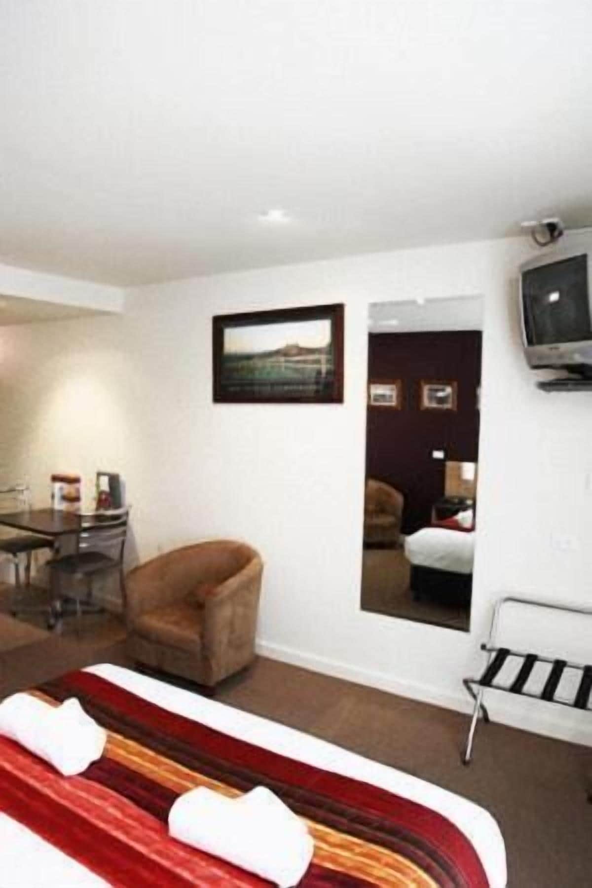 Une chambre d’hôtel avec un lit, une chaise, une télévision et un bureau avec une chaise.