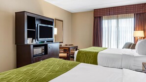 A hotel room with two beds, a desk with a computer, a microwave, and a television.