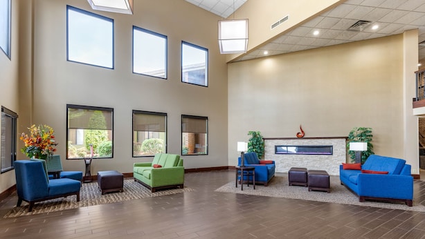 A spacious lobby with a high ceiling, large windows, and a fireplace. There are multiple seating areas with sofas and chairs.