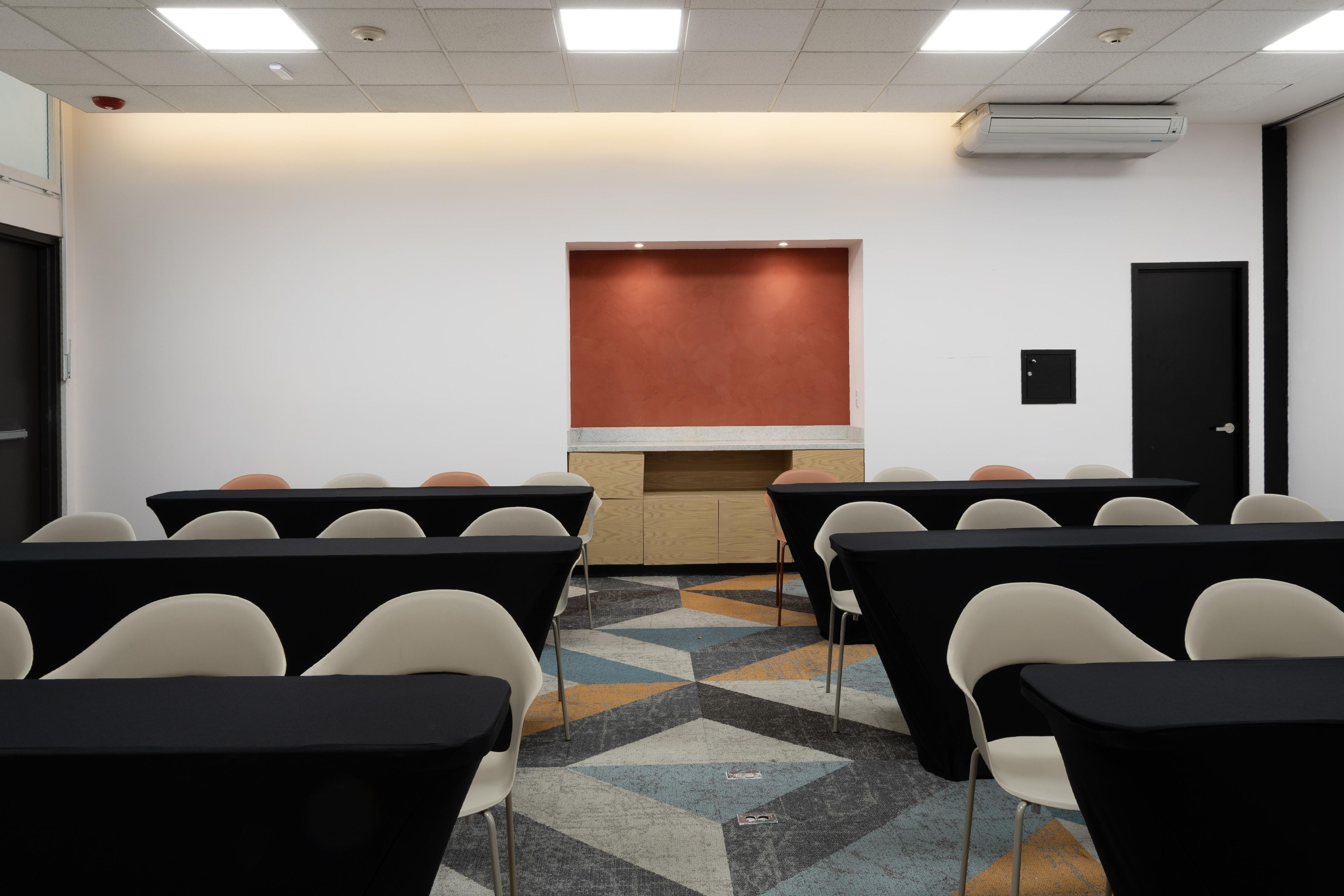 Ein Konferenzraum mit Projektorleinwand, einer Tür und einem gemusterten Teppich.