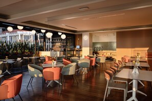 Un restaurant moderne avec un intérieur élégant, plusieurs espaces de restauration, un bar et une vue sur le paysage urbain.