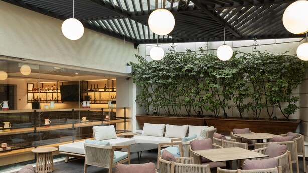 Un restaurante con mobiliario de mimbre, una zona de bar y una pared cubierta de vegetación.