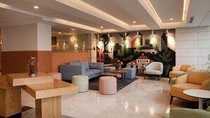 Un moderno vestíbulo de hotel con un sofá, una otomana, una mesa de centro y sillas.