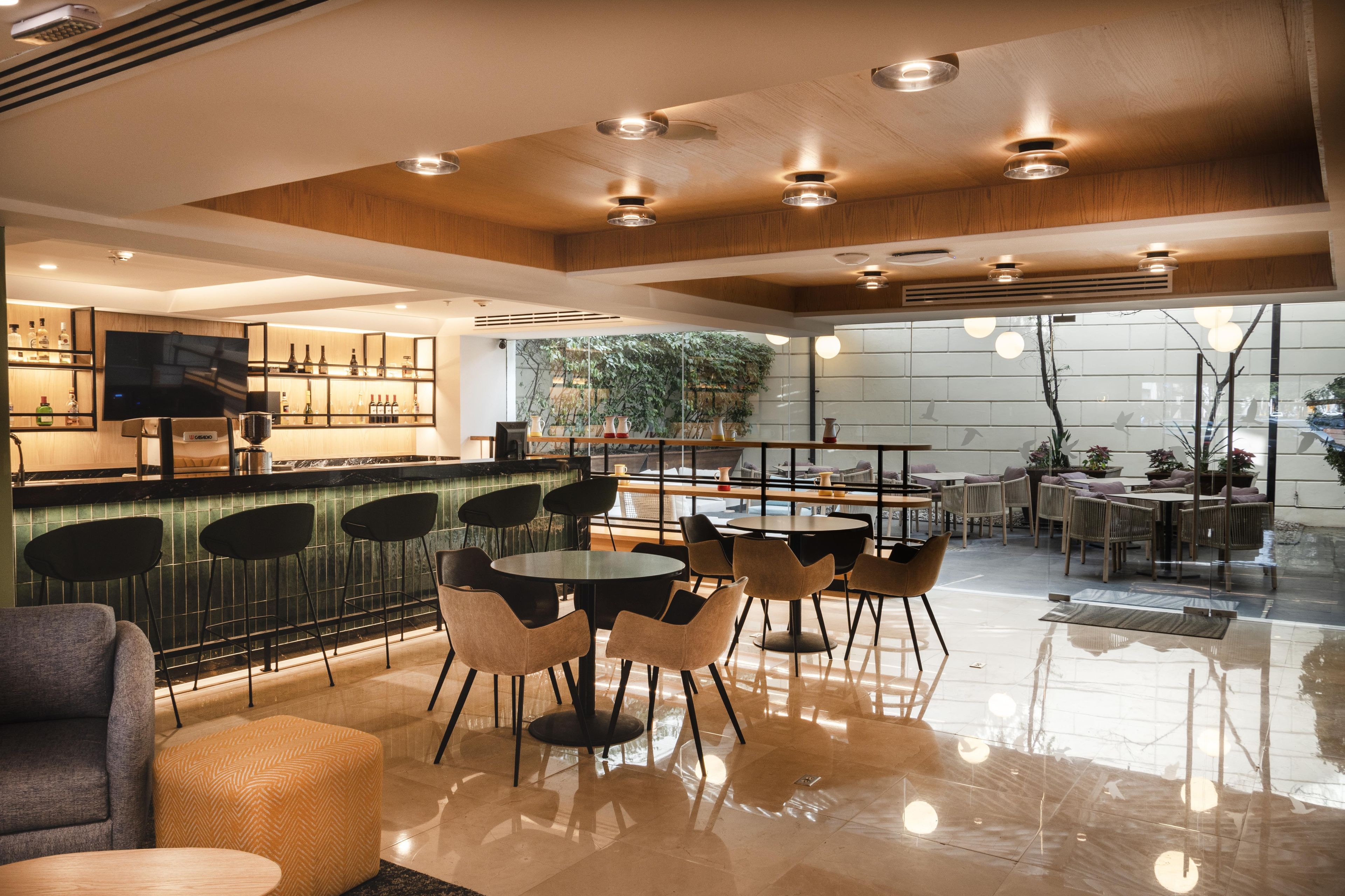 Zona de bar moderna con televisor, taburetes y una variedad de botellas.