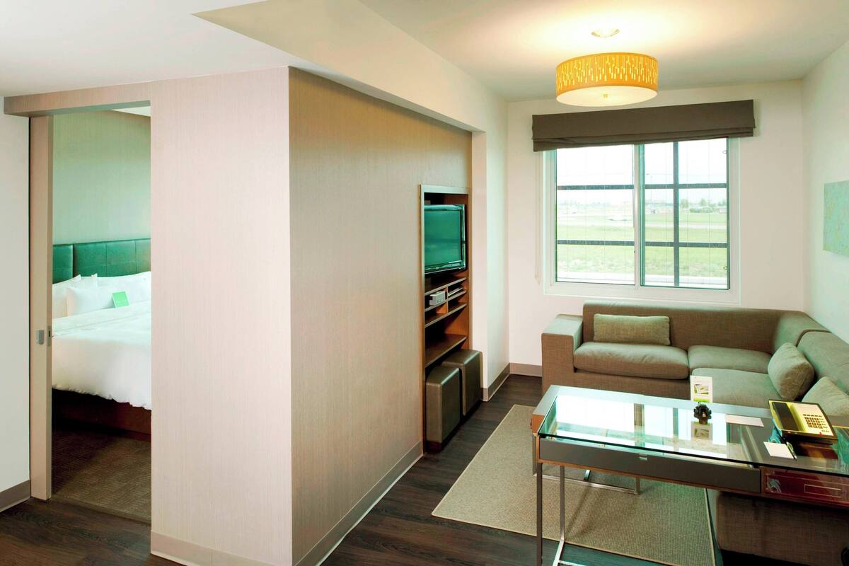 Une chambre d’hôtel avec un lit, une télévision, un canapé et une fenêtre donnant sur un paysage agréable.
