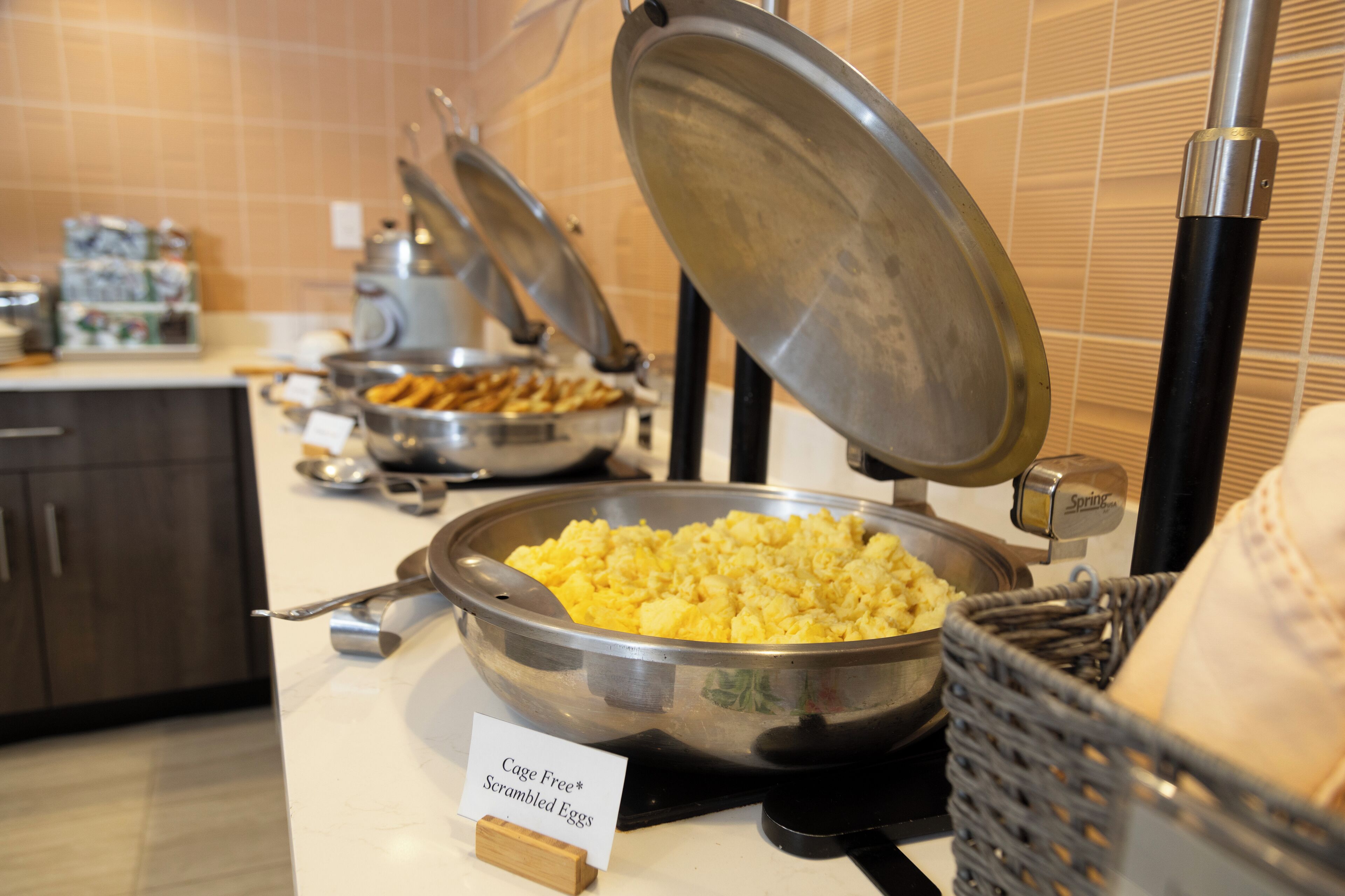 Un buffet proposant une variété de plats, notamment des œufs brouillés, des frites et d’autres mets.