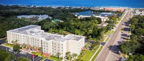 A multi-story hotel with a parking lot and a road in the foreground.