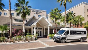 A hotel entrance with a covered walkway, bicycles, and a van parked in front.