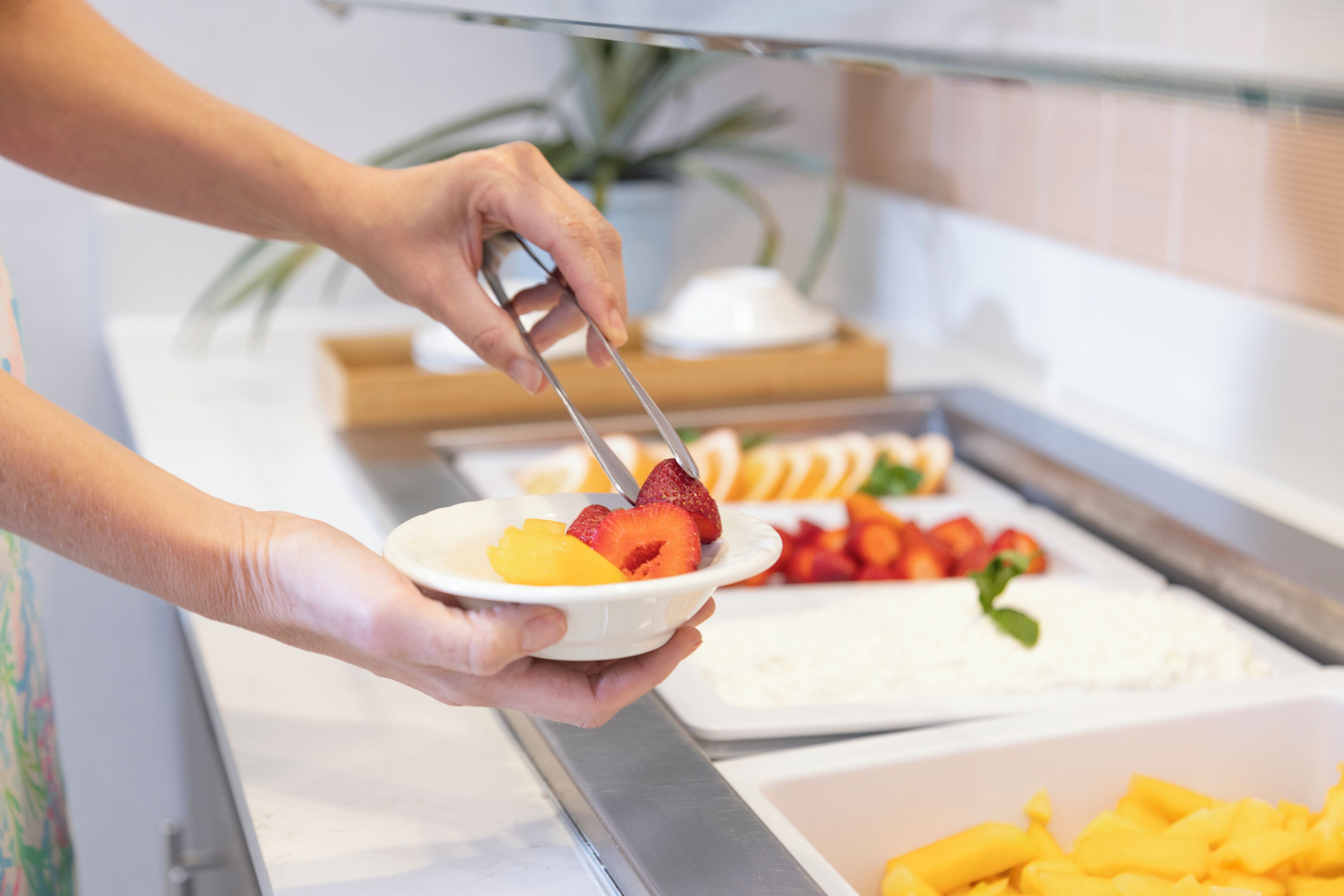 A buffet with various food items, including fruits and a white dish with a spoon.