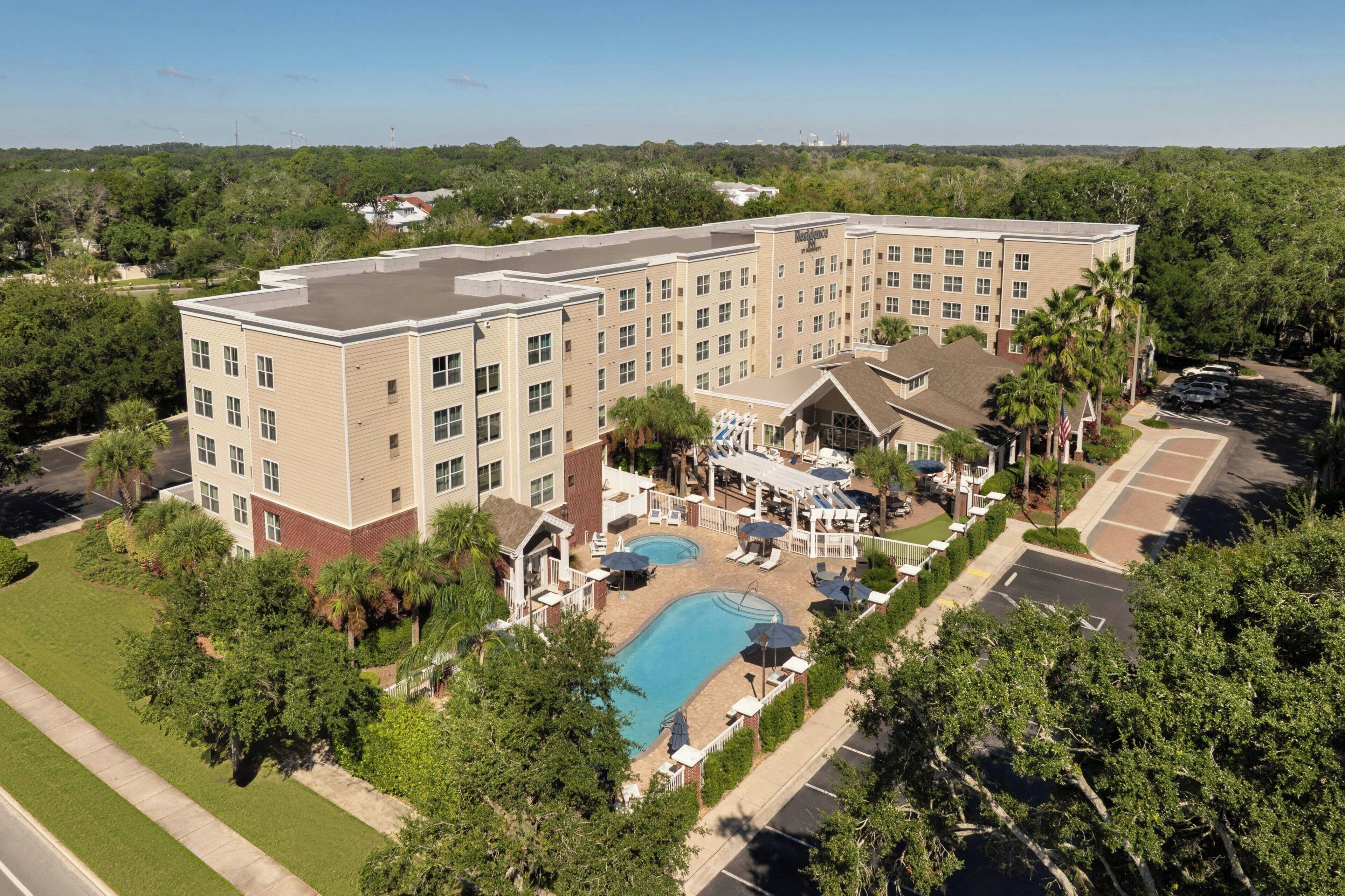 A hotel with multiple floors, a swimming pool, and a parking area.